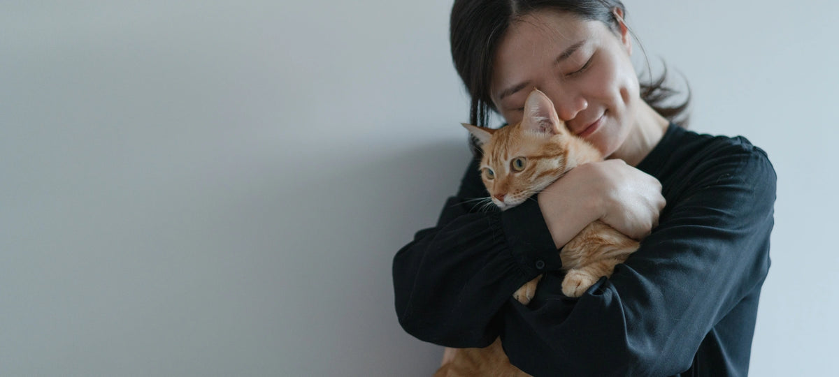 Woman holding a cat against a plain background